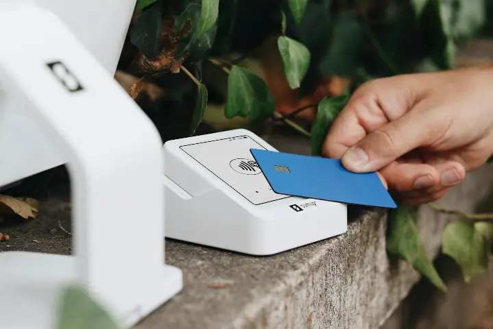 A person holding a credit card next to a machine